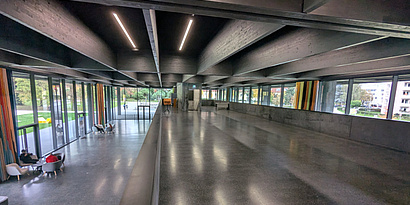 Interior view of Kepler Hall during daylight, showing a spacious and empty area with high ceilings and large windows, allowing natural light to illuminate the space.